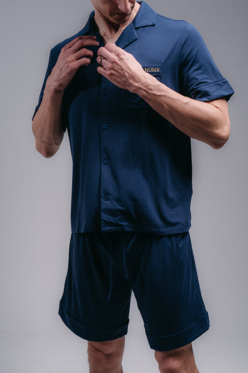 Man wearing a navy blue pjs with a logo on a gray background