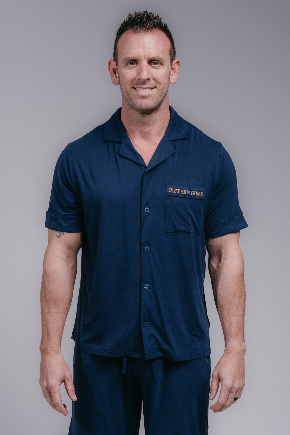 Man wearing a navy blue pjs with a logo on a gray background