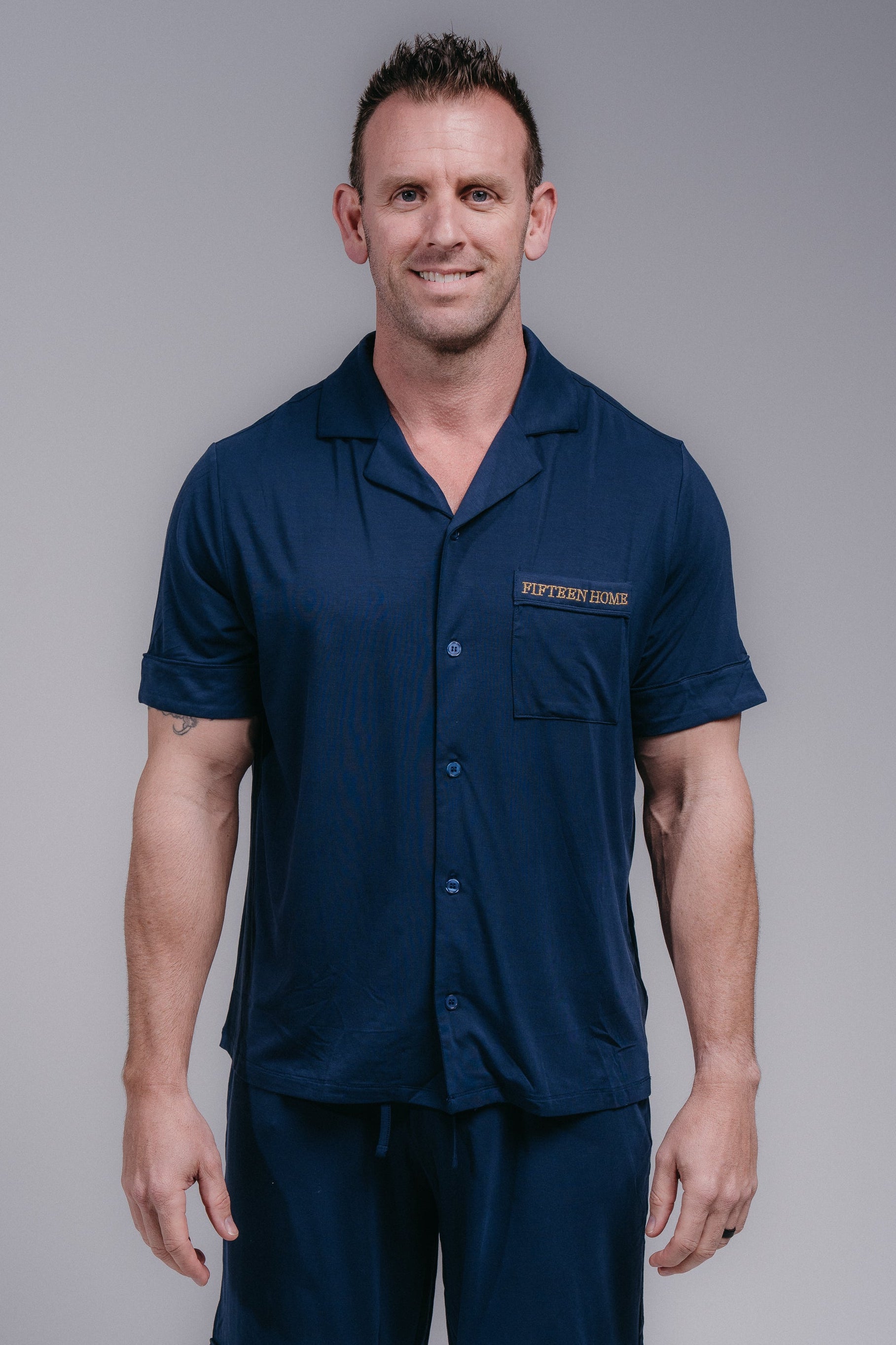 Man wearing a navy blue pjs with a logo on a gray background