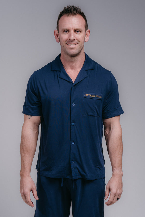 Man wearing a navy blue pjs with a logo on a gray background